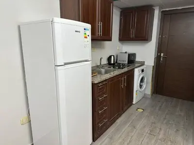 a kitchen with a white refrigerator and a washer and dryer at استوديو مفروش لشخصين الجاردنز 320 in Amman