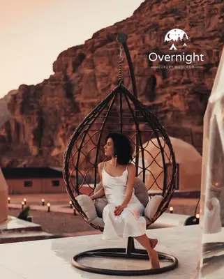 a woman sitting in a swing in the desert at Rum Overnight luxury& jeep in Wadi Rum
