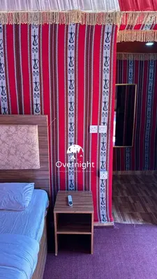 a bedroom with a bed and a table and a curtain at Rum Overnight luxury& jeep in Wadi Rum