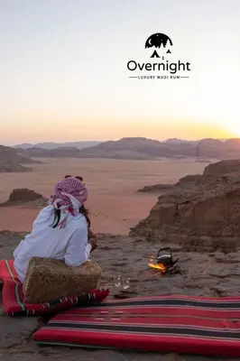 a couple sitting in the desert watching the sunset at Rum Overnight luxury& jeep in Wadi Rum