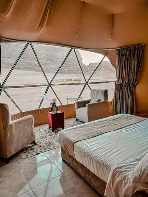 a bedroom with a large bed and two chairs at Rum thabit camp in Wadi Rum