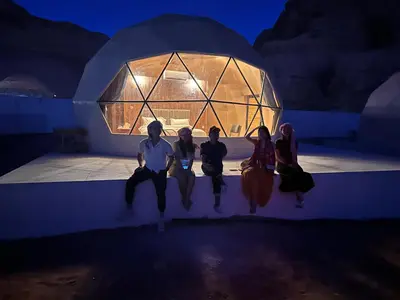 a group of people sitting on a stage at night at Rum thabit camp in Wadi Rum
