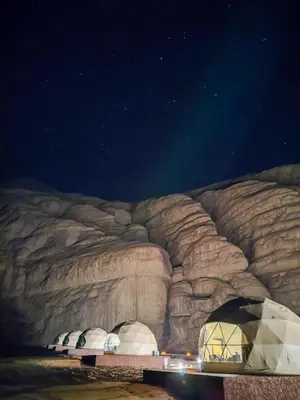 a group of domes in front of a rock wall at Rum thabit camp in Wadi Rum