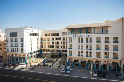 a large white building with a sign on it at Golden Tulip Amman in Amman