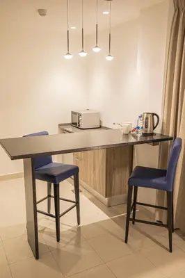 a kitchen with a table and two blue chairs at Golden Tulip Amman in Amman