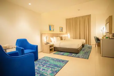 a hotel room with a bed and a blue chair at Golden Tulip Amman in Amman