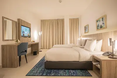 a hotel room with two beds and a desk at Golden Tulip Amman in Amman
