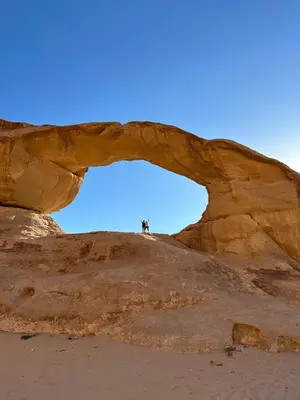 a person standing under an arch in the desert at WADI RUM AJWAN lUXURY CAMP in Wadi Rum