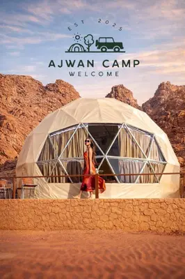 a woman standing in front of a tent in the desert at WADI RUM AJWAN lUXURY CAMP in Wadi Rum