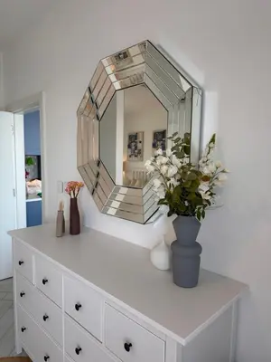 a mirror on top of a dresser with a vase with flowers at Chic One-Bedroom with Sea View in Aqaba