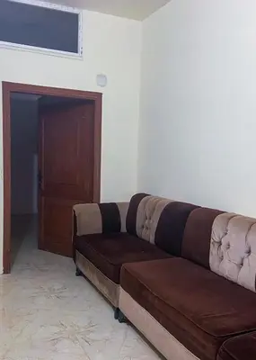 a brown couch in a living room with a door at روابي عجلون منزل in Ajloun