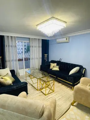 a living room with a black couch and a glass table at Cozy 2 bedroom apartment in Amman