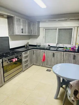 a kitchen with wooden cabinets and a table in it at Cozy 2 bedroom apartment in Amman