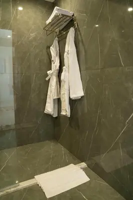 a bathroom with a shower with white robes at Sea Gate Resort in Sowayma