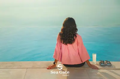 a woman sitting on a ledge looking at the water at Sea Gate Resort in Sowayma