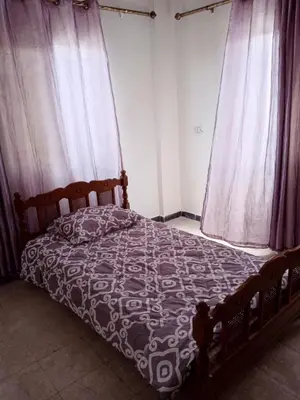 a bedroom with a bed with a comforter and two windows at شقة ام نوارة الحديثة الفارهة spacious economic flat in Amman