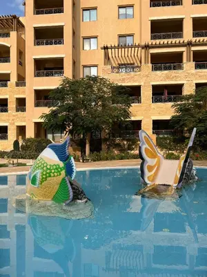 two chairs in a swimming pool in front of a building at B36 Loft Apartment Samarah Resort in Sowayma