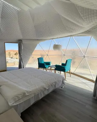 a bedroom with a bed and two blue chairs at Rum Leno Luxure camp in Wadi Rum