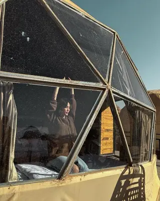 a man is looking out the window of a house at Rum Leno Luxure camp in Wadi Rum