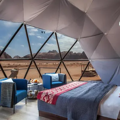 a room with a bed and two chairs in a tent at Rum Leno Luxure camp in Wadi Rum
