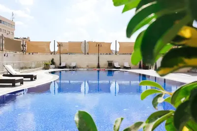 a large swimming pool with chairs and a building at Grand Days Hotel & Suites Amman in Umm Uthainah