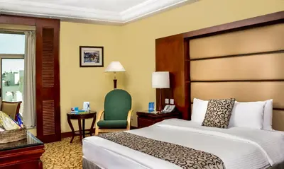 a hotel room with a bed and a green chair at Grand Days Hotel & Suites Amman in Umm Uthainah