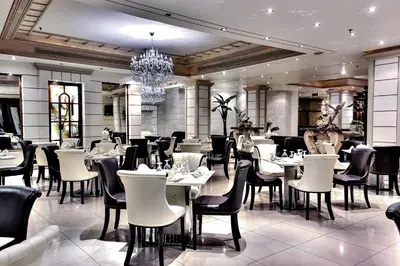 a restaurant with tables and chairs and a chandelier at Grand Days Hotel & Suites Amman in Umm Uthainah