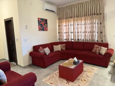 a living room with a red couch and a table at Cozy Flat, Amman Airport in Amman