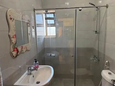 a bathroom with a sink and a glass shower at Cozy Flat, Amman Airport in Amman