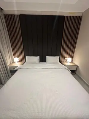 a large white bed in a room with two lamps at Chic Apartments For Rent ave2-8 in Amman
