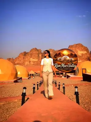 a woman walking down a red path in the desert at RUM MARS VALLEY BUBBLE lUXURY CAMP in Wadi Rum