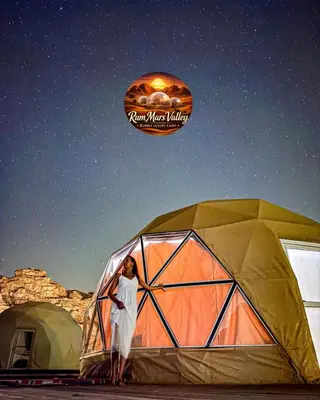 a woman is standing in front of a tent at RUM MARS VALLEY BUBBLE lUXURY CAMP in Wadi Rum