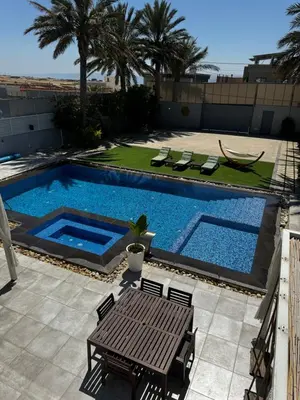 a swimming pool with a table and chairs next to it at Maui Villa by Seahorse in Al Rama