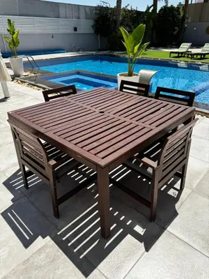 a wooden table and chairs next to a swimming pool at Maui Villa by Seahorse in Al Rama