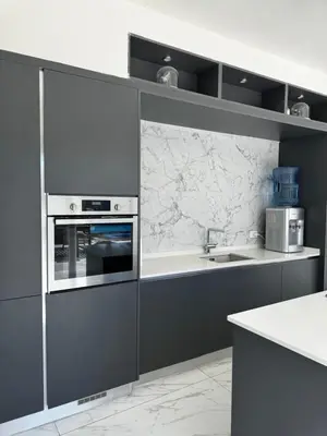 a kitchen with gray cabinets and a marble wall at Maui Villa by Seahorse in Al Rama