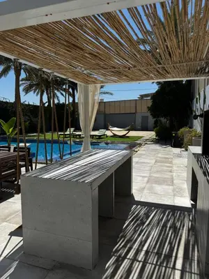 a concrete bench under a pavilion with a pool at Maui Villa by Seahorse in Al Rama