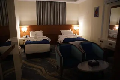 a hotel room with two beds and a chair at فندق أوتار ذهب in Ma‘ān