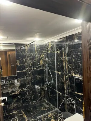 a bathroom with a black tiled wall at City Rose Hotel Suites in Amman