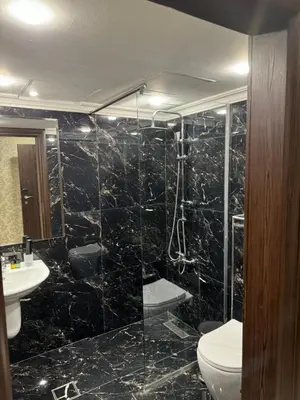 a bathroom with a shower with a toilet and a sink at City Rose Hotel Suites in Amman