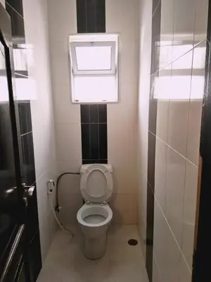 a small bathroom with a toilet and a window at zin home in ‘Awjān ash Sharqī
