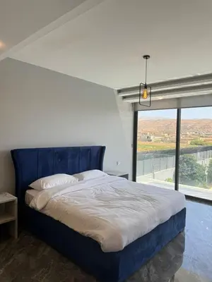 a bedroom with a blue bed with a large window at Maria La Rosa By Seahorse in Al Baḩḩāth