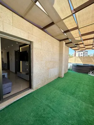 an outdoor patio with a green floor and a building at Rooftop pool with terraces F-R in Amman