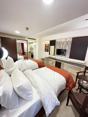 a hotel room with three beds and a television at Londrina Hotel in Amman