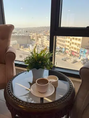 a coffee table with a cup of coffee and a plant at Londrina Hotel in Amman