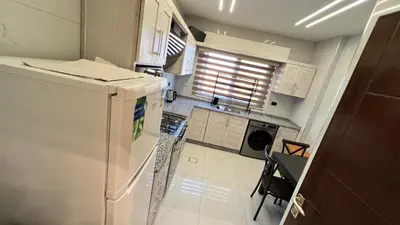 a kitchen with a refrigerator and a table and chairs at شقة مفروشة فخمة بغرفتين نوم عمو سامي in Amman