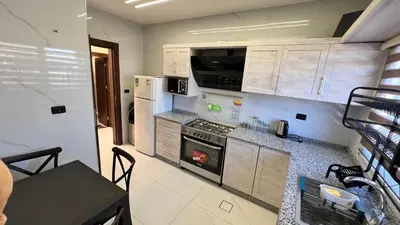 a kitchen with white cabinets and a stove top oven at شقة مفروشة فخمة بغرفتين نوم عمو سامي in Amman