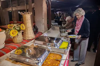 a woman holding a plate of food at a buffet at Desert Sand Camp in Disah