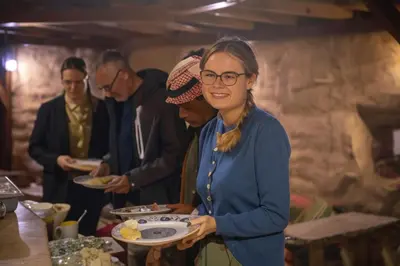 a woman with glasses holding a plate of food at Desert Sand Camp in Disah