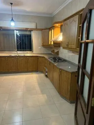 a kitchen with wooden cabinets and a stove top oven at olga 300 apertment in Ar Ramthā
