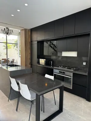 a kitchen with black cabinets and a table and chairs at Beit Elhala Villa By Seahorse in Al Rama